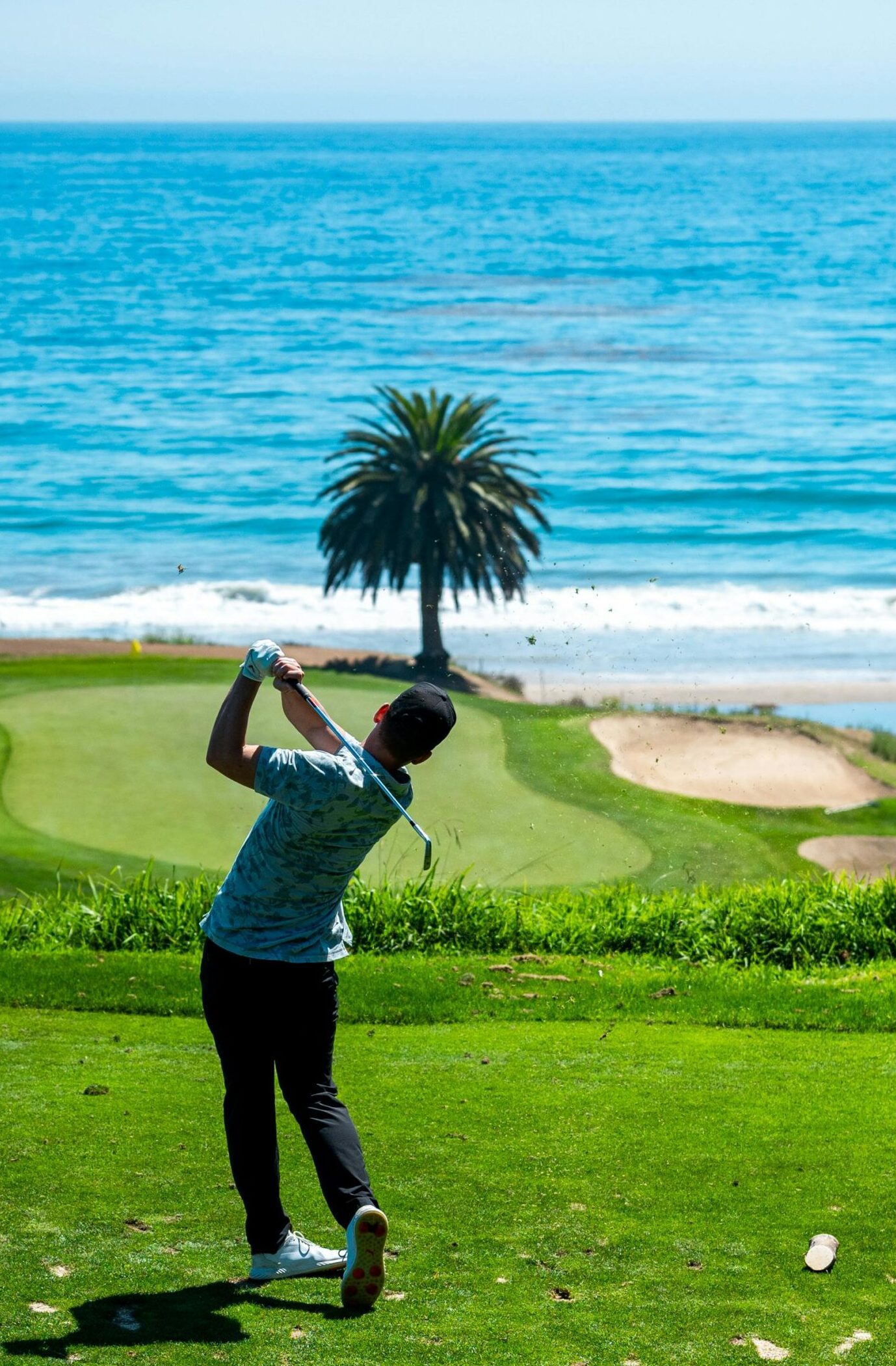 Golfer swinging on a picturesque golf course by the ocean in Santa Barbara, CA.